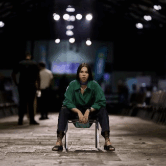 María Lucía Alpízar Porras sitting on a chair in the middle of a warehouse.